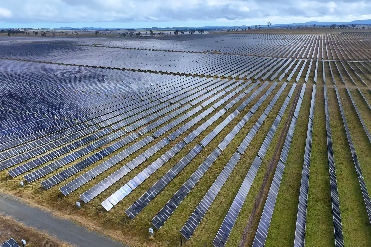 Aerial view of a large solar farm with long rows of panels across open land
